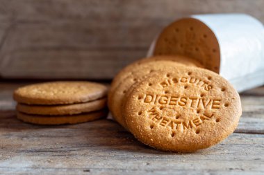 Sindirim bisküvileri ahşap bir zemine saçılmış. Kurabiyelerin üzerinde bisküvi sindirim buğdayını okuyabilirsin.- 
