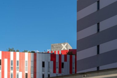 Mavi gökyüzünün aksine metal çizgileri, kırmızı, beyaz ve gri renkleri olan modern bir binaya odaklan.