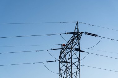 Mavi gökyüzüne karşı yüksek voltajlı elektrik kulesi