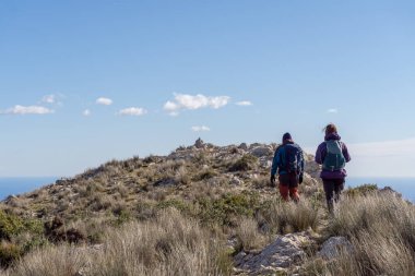 Güneşli bir günde dağda yürüyen yürüyüşçüler.