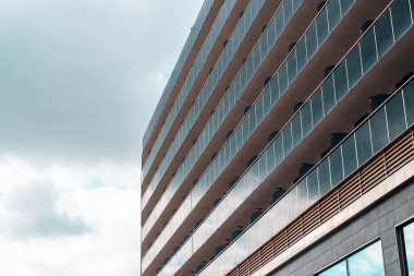 Bulutlu gökyüzüne karşı modern bir binanın donuk cephesi.