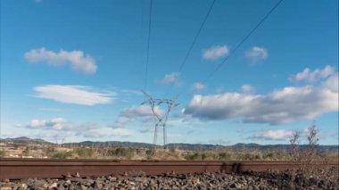 Gökyüzünde bulutlar uçuşan yüksek voltajlı bir elektrik kulesinin hızlandırılmış videosu..