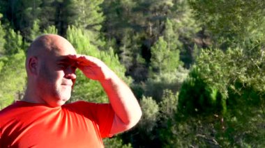 Slow motion, the man puts his hand on his forehead to see better in direct sunlight