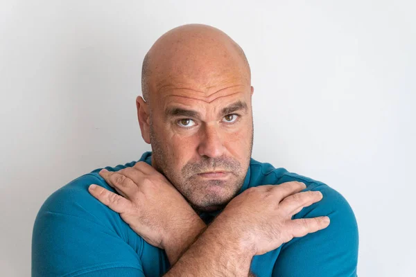 Portrait of a middle-aged Caucasian man with a serious and defiant look, with his hands on his shoulders, on a white background.