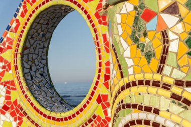 Deniz ve gökyüzü manzarası, Akdeniz Trencads tarzında yapılmış bir heykelin deliğinden