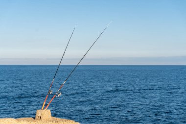Arkasında deniz olan iki izole olta kamışı.