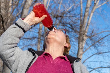  Yaşlı kadın plastik şişeden izotonik içecek içiyor.