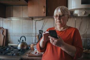 Endişeli orta yaşlı kadın cep telefonu ekranına bakıyor..