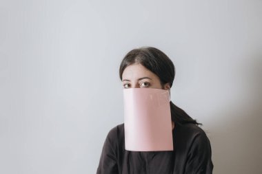 Güzel Asyalı kadın yüzüne kağıt örtü takıyor. Beyaz arka plan.