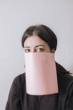 Güzel Asyalı kadın yüzüne kağıt örtü takıyor. Beyaz arka plan.