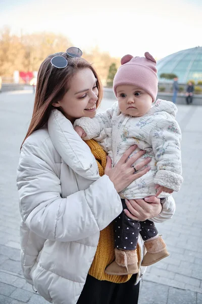 Anne kucağında kameraya gülümseyen bir bebek. Gerçek hayatta sıradan bir anne kameraya bakar.