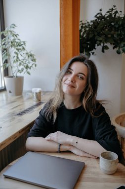 Serbest çalışan bir kadın, kumral bir kafede çalışmaktan memnun.