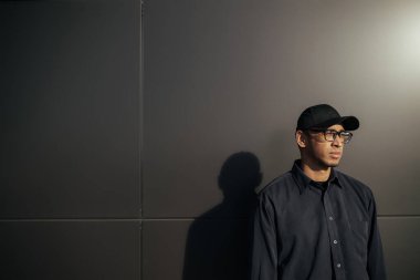 Sokakta poz veren sakallı ve şapkalı siyah bir adamın portresi.