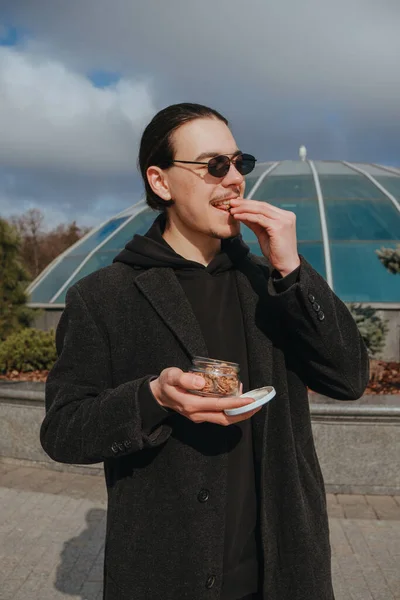 Νεαρός Γκέι Χίπστερ Τρώει Φιστίκια Στο Δρόμο Χαμογελώντας Χαρούμενα Γυαλιά — Φωτογραφία Αρχείου