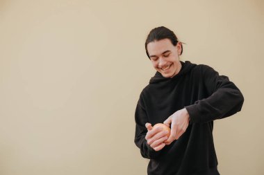 20 'li yaşlarda sakallı, beyaz tişörtlü, elinde mavi pastel arka plan stüdyo portresi ile izole edilmiş greyfurtun yarısını tutan genç bir adam. Cilt bakımı kozmetik işlemleri konsepti. Kopyalama alanı oluştur