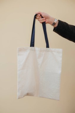 Renkli arka planda tekstil çantası tutan genç adam, yakın plan. Tasarım hipster için model