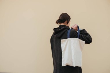 Renkli arka planda tekstil çantası tutan genç adam, yakın plan. Tasarım hipster için model