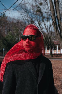 Kırmızı maskeli ve güneş gözlüklü süper kahraman parkta moda savaşçısı.