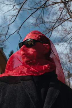 Kırmızı maskeli ve güneş gözlüklü süper kahraman parkta moda savaşçısı.