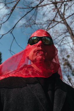 Kırmızı maskeli ve güneş gözlüklü süper kahraman parkta moda savaşçısı.