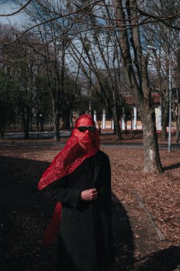 Kırmızı maskeli ve güneş gözlüklü süper kahraman parkta moda savaşçısı.