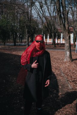 Kırmızı maskeli ve güneş gözlüklü süper kahraman parkta moda savaşçısı.