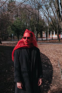 Kırmızı maskeli ve güneş gözlüklü süper kahraman parkta moda savaşçısı.