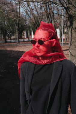 Kırmızı maskeli ve güneş gözlüklü süper kahraman parkta moda savaşçısı.