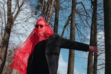 Kırmızı maskeli ve güneş gözlüklü süper kahraman parkta moda savaşçısı.