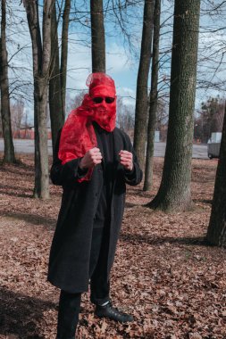 Kırmızı maskeli ve güneş gözlüklü süper kahraman parkta moda savaşçısı.