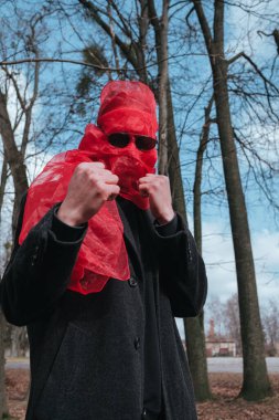 Kırmızı maskeli ve güneş gözlüklü süper kahraman parkta moda savaşçısı.