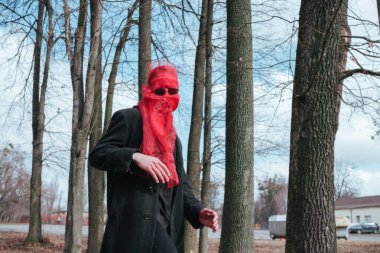 Kırmızı maskeli ve güneş gözlüklü süper kahraman parkta moda savaşçısı.