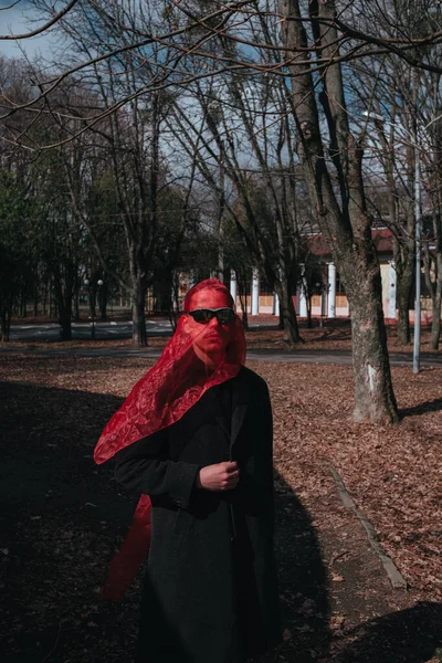 Kırmızı maskeli ve güneş gözlüklü süper kahraman parkta moda savaşçısı.