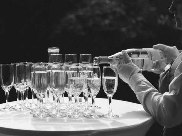 Наливание шампанского для тоста в праздничной атмосфере с бокалами шампанского на золотые хлопья эффект боке зерна — стоковое фото