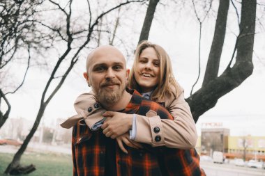 Birbirini seven çiftler birbirlerine sarılırlar. Arkaplanda ağaç