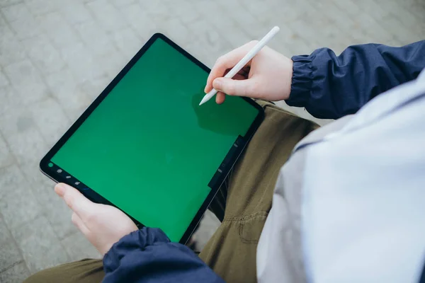 Zdola hipster muž pomocí moderní tablet s stylus při vytváření nového projektu a posezení na ulici — Stock fotografie