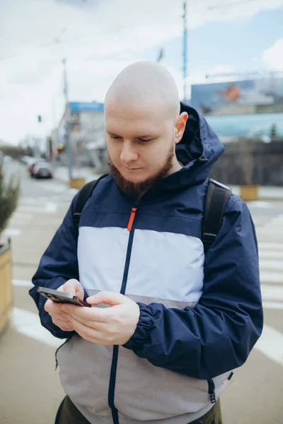 若いアイルランド人の男は、市内でスマートフォンを使用して幸せな笑顔. — ストック写真