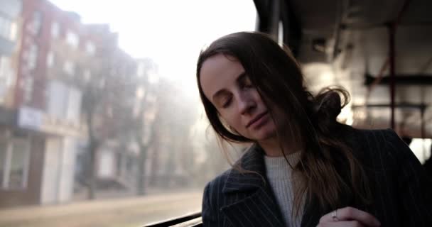 Mladá žena se smutně dívá z okna autobusu, nosí sluchátka — Stock video