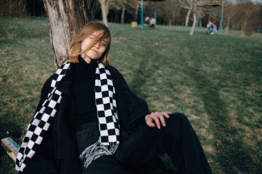 Bir kızın portresi Parkta otururken ağaçların arkasında