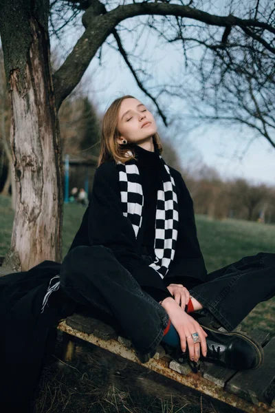 Bir kızın portresi Parkta otururken ağaçların arkasında