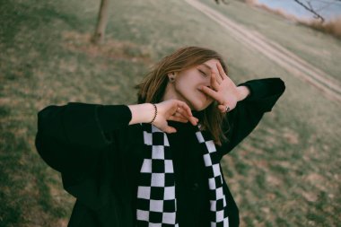 İskandinav kız, gri günlük modern giysiler içinde, bir ağacın yanında dans ediyor.