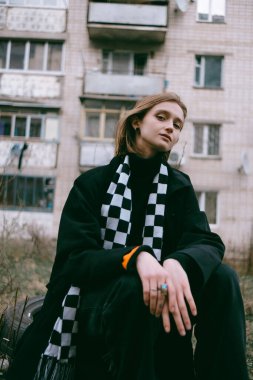 Ukrayna 'daki eski bir binanın arka planında oturan sarı saçlı üzgün mülteci kız..