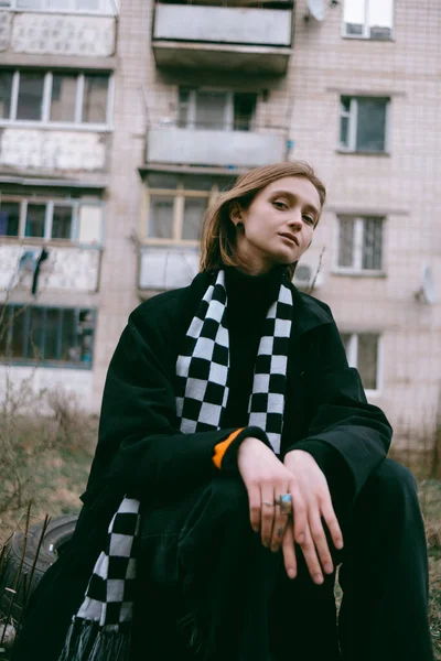 Ukrayna 'daki eski bir binanın arka planında oturan sarı saçlı üzgün mülteci kız..