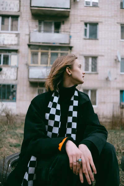 Ukrayna 'daki eski bir binanın arka planında oturan sarı saçlı üzgün mülteci kız..