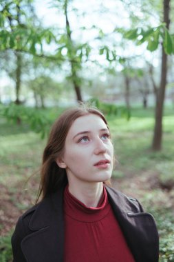 Güzel sarışın bir kız yukarı bakıyor. İlkbaharda ormanın portresi.