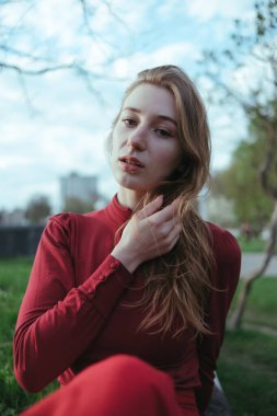 Kırmızılı sarışın bir kız şehirde oturuyor, saçları rüzgar tarafından büyütülüyor.