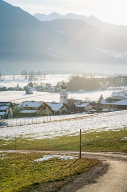 Dağlardaki güneşli köy kilisesi. Eriyen karlar çayırları, yabani otları, Tirol, Avusturya 'yı aydınlatıyor.