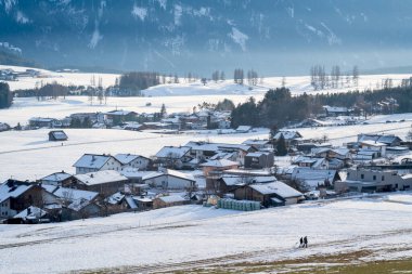 Soğuk kar altında yürürken Avusturya, Tirol, Wildermieming dağ köyünde kış manzarası kaplandı.