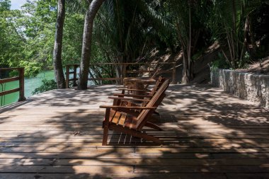 Mopan nehri, Bullet Tree Şelalesi, Belize 'de yemyeşil tropikal ormanlarla çevrili ahşap sandalyeli Idyllic nehir kenarı rıhtımı.