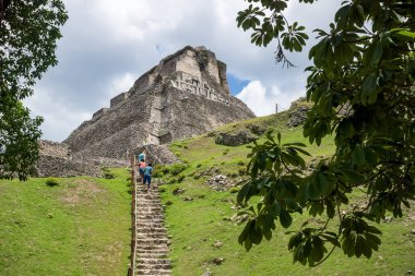 San Ignacio, Belize - 24 Ağustos 2019: Xunantunich arkeoloji sahasındaki 'El Castillo' harabesi güneşli Maya 'ya giden dik merdivenleri tırmanan turistler